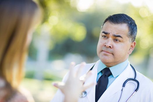 Hispanic Male Doctor or Nurse Talking With a Patient Outdoors.