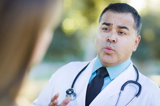 Hispanic Male Doctor or Nurse Talking With a Patient Outdoors.