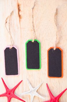 Wooden tag label on and star fish on wooden background.