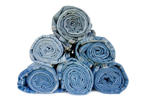 roll blue denim jeans arranged in stack on white background