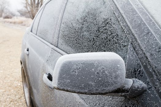 Sedan that has been frozen over with focus on the side mirror