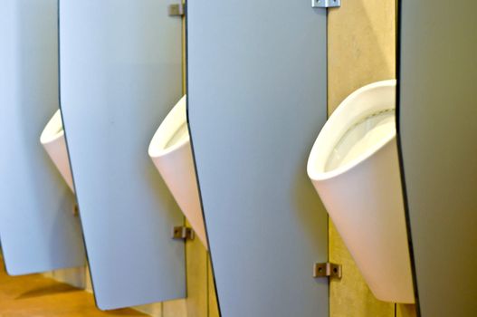 Urinals behind partitions in a toilet in office building