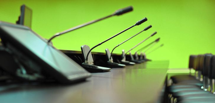 Conference table, microphones and office chairs, closeup, green
