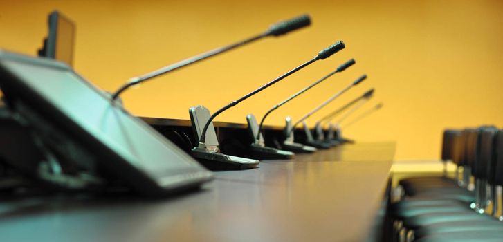 Conference table, microphones and office chairs, closeup, orange