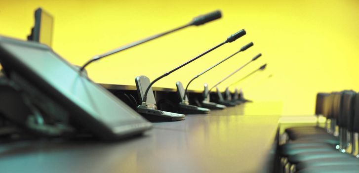 Conference table, microphones and office chairs, closeup, yellow