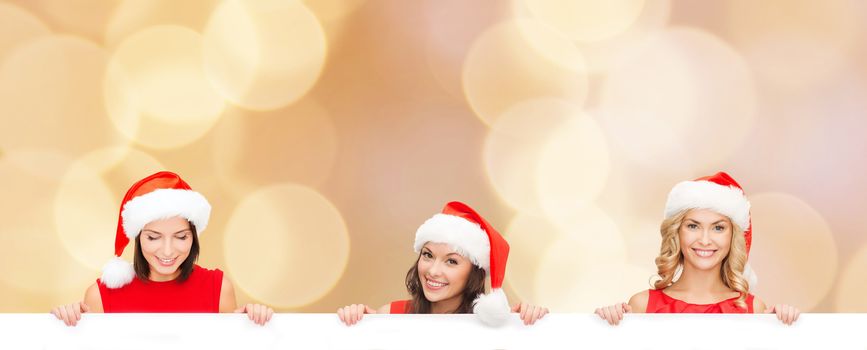 christmas, x-mas, people, advertisement and sale concept - happy women in santa helper hat with blank white board over beige lights background