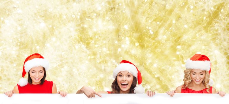 christmas, x-mas, people, advertisement and sale concept - happy women in santa helper hat with blank white board over yellow lights background