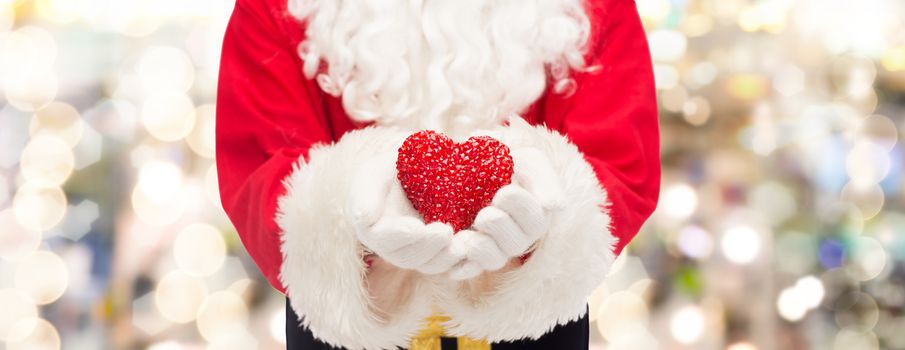 christmas, holidays, love, charity and people concept - close up of santa claus with heart shape decoration over lights background