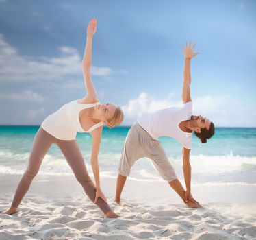 fitness, sport, friendship and lifestyle concept - couple making yoga exercises on summer beach
