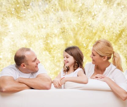 family, childhood, holidays and people - smiling mother, father and little girl over yellow lights background