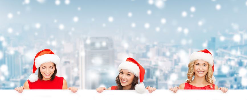 christmas, x-mas, people, advertisement and sale concept - happy women in santa helper hat with blank white board over snowy city background