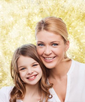 family, childhood, happiness and people - smiling mother and little girl over yellow lights background