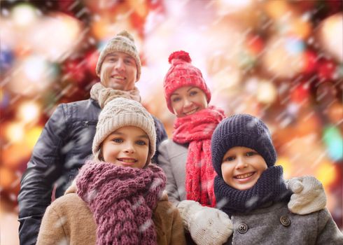 family, childhood, season, holidays and people concept - happy family in winter clothes over red lights and snow background