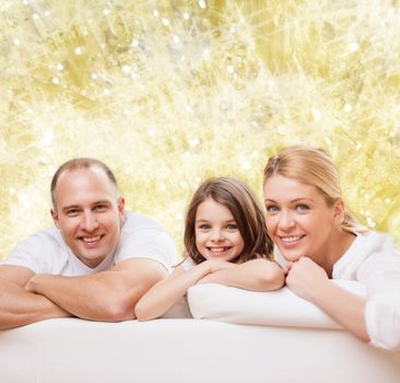 family, childhood, holidays and people - smiling mother, father and little girl over yellow lights background