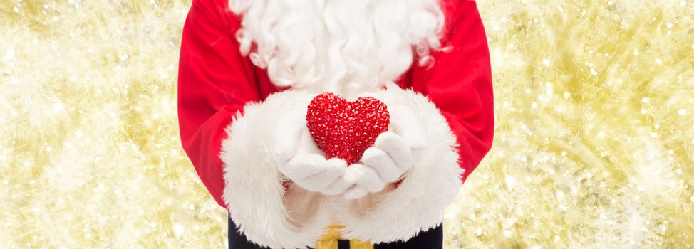 christmas, holidays, love, charity and people concept - close up of santa claus with heart shape decoration over yellow lights background