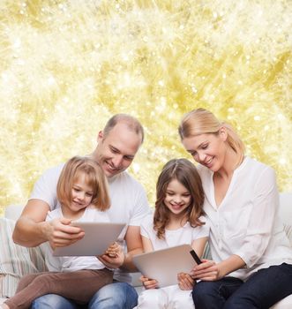 family, holidays, technology and people - smiling mother, father and little girls with tablet pc computers over yellow lights background