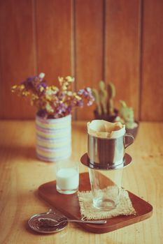 Empty vintage glass with Vietnamese style dripper on wood table in cafe, ready for dripping coffee or tea with vintage filter effect