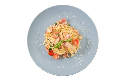 Pasta with bacon and tomato in grey ceramic dish isolated on white background with clipping path