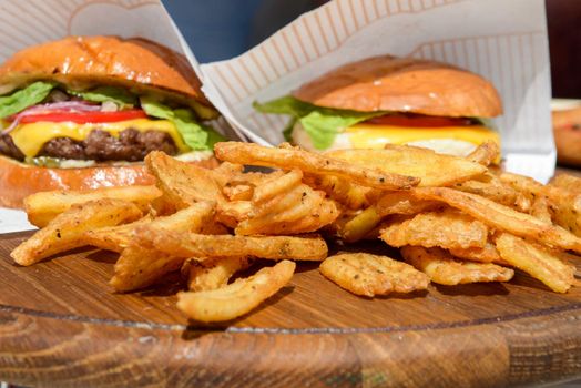 fresh burgers and fries on a wooden tray