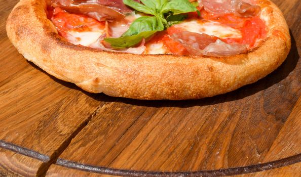 Fresh pizza on a thick dough on a wooden tray