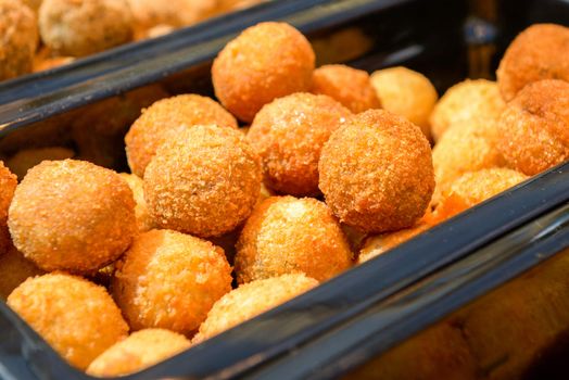 ruddy crispy cheese balls with spices in a metal tray