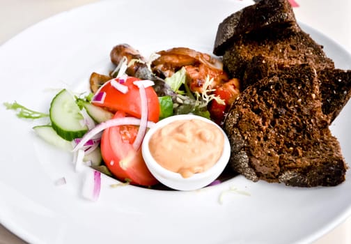 dish of tomatoes and meat with brown bread on a white plate