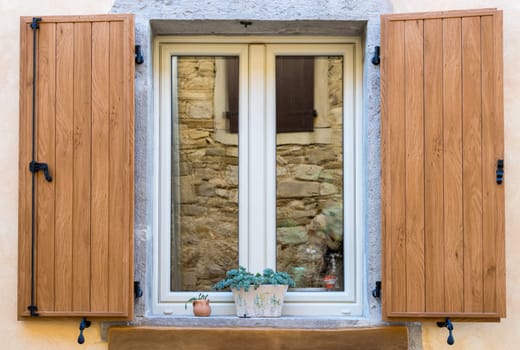 a nice window with open brown  wooden shutters and flowers in the pot