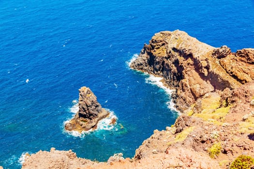 Madeira - cliff coast with rock needle in bay - surge of waves of the Atlantic Ocean