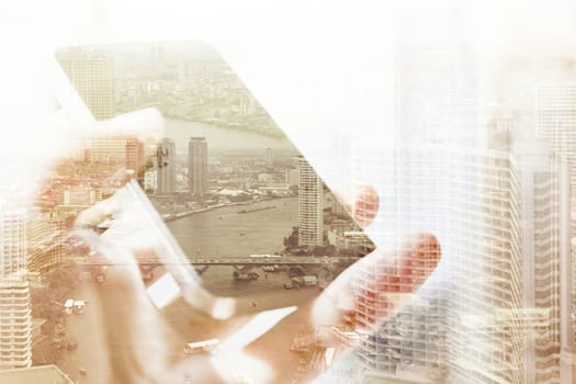 Double exposure of cityscape and smart phone, business technology concept.