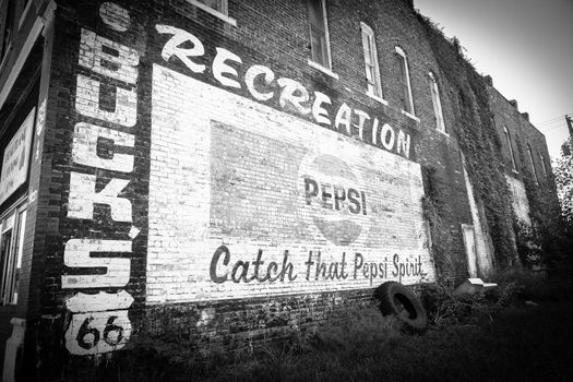 Old faded vintage painted sign on brick wall on Route 66 black and white with Pepsi and old fashioned vignette effect.