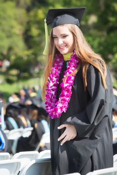 Happy college graduate walking between chairs outdoors