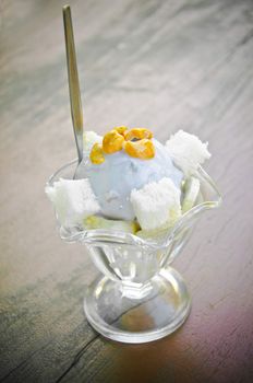 Taro ice cream with cashew in glass cup on wood table.