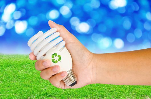 Hand with lamp and sign recycle on spring background