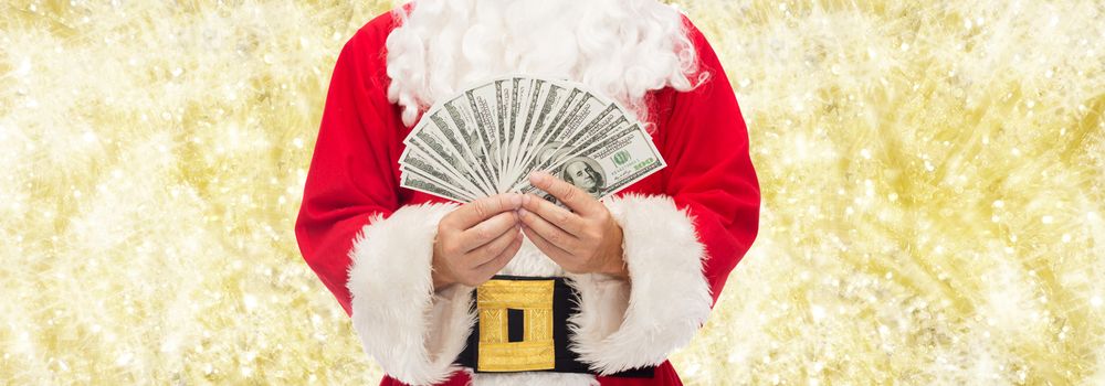 christmas, holidays, winning, currency and people concept - close up of santa claus with dollar money over yellow lights background