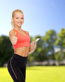 sport, fitness, technology, internet and healthcare concept - smiling sporty woman with smartphone showing thumbs up