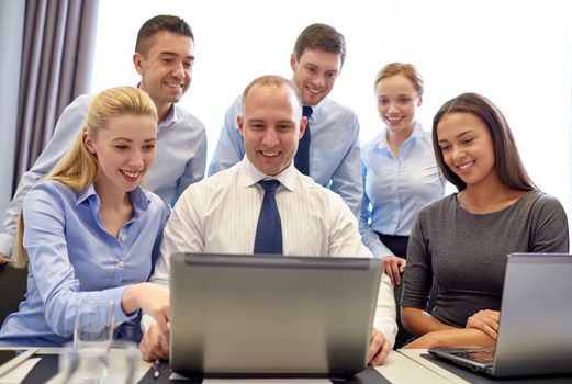 business, people, technology and communication concept - smiling business team with laptop computer making video conference in office