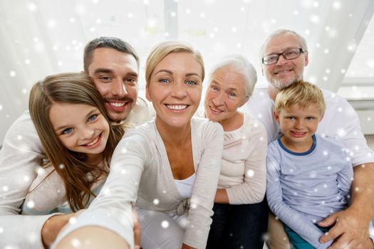 family, technology, generation and people concept - happy family sitting on couch and taking self portrait with camera or smartphone at home