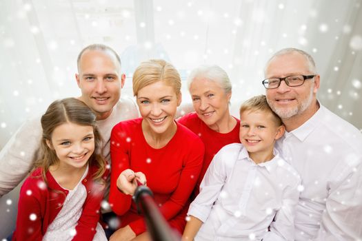 family, holidays, generation, christmas and people concept - smiling family with camera and selfie stick taking picture at home