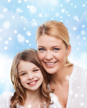 family, childhood, happiness and people - smiling mother and little girl over blue sky and snow background