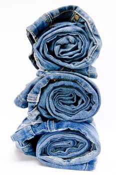 roll blue denim jeans arranged in stack on white background