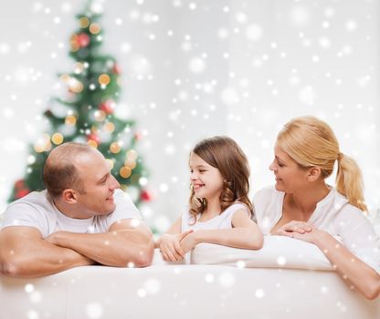 family, childhood, holidays and people - smiling mother, father and little girl over living room and christmas tree background