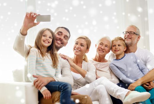 family, happiness, generation and people concept - happy family sitting on couch and taking selfie with smartphone at home
