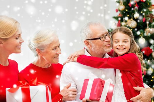 family, holidays, generation, christmas and people concept - smiling family with gift boxes hugging and kissing at home