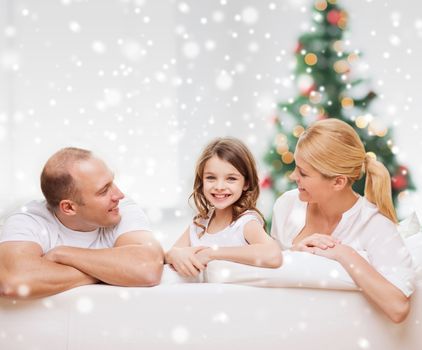 family, childhood, holidays and people - smiling mother, father and little girl over living room and christmas tree background