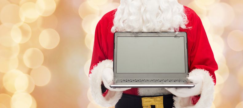 christmas, advertisement, technology, and people concept - close up of santa claus with laptop computer over beige lights background