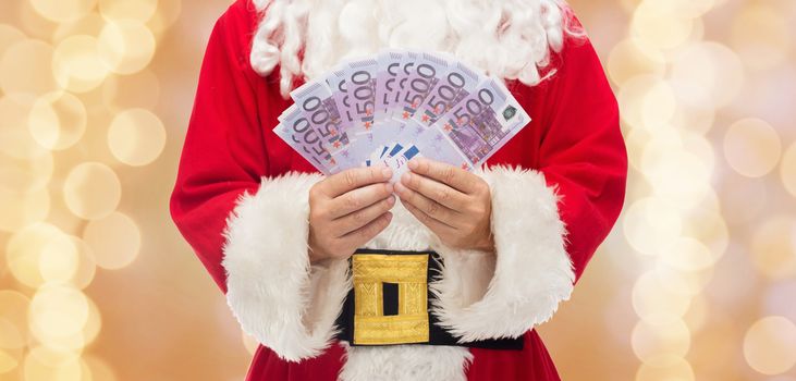 christmas, holidays, winning, currency and people concept - close up of santa claus with euro money over beige lights background