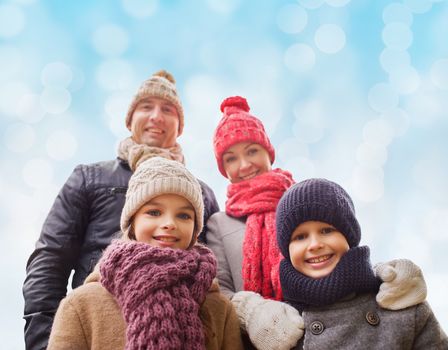 family, childhood, season and people concept - happy family in winter clothes over blue lights background