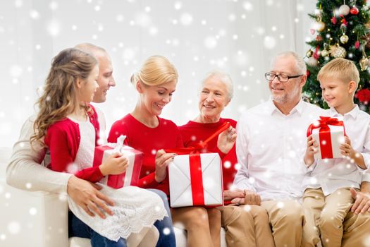 family, holidays, generation, christmas and people concept - smiling family with gift boxes sitting on couch at home