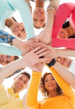 friendship, youth and people concept - group of smiling teenagers with hands on top of each other