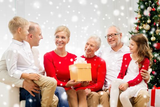 family, holidays, generation, christmas and people concept - smiling family with gift box sitting on couch at home